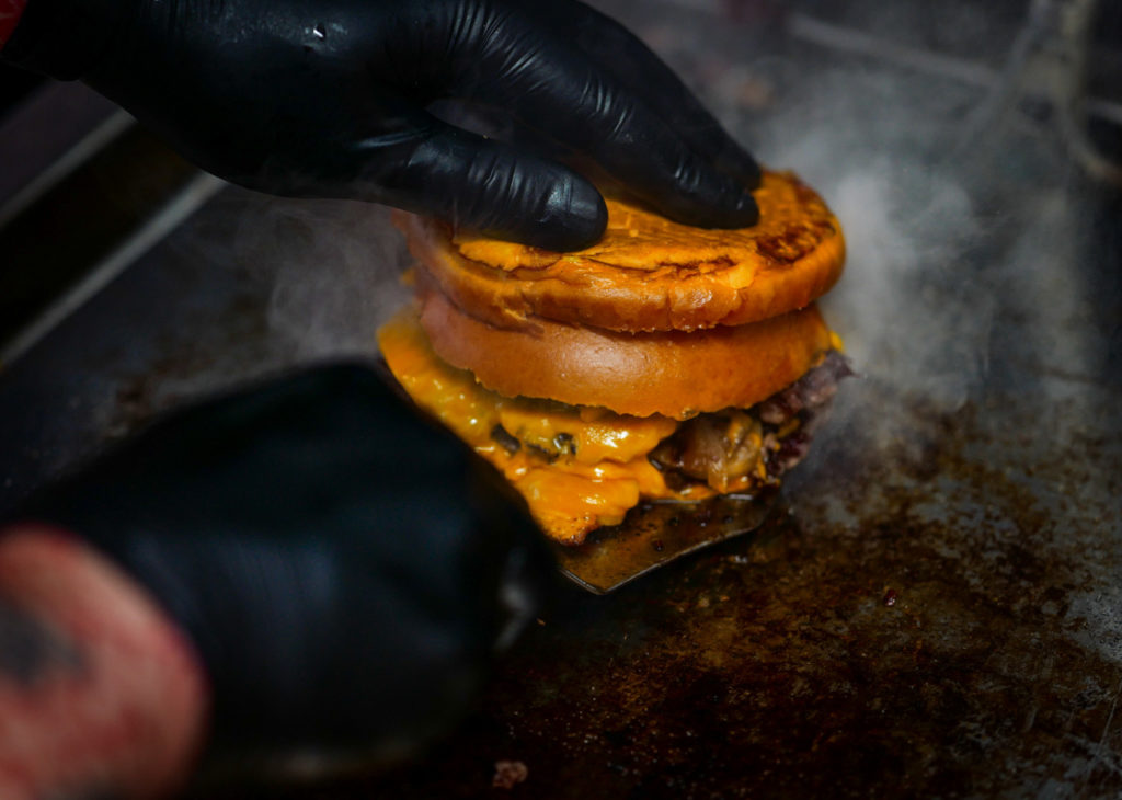 Burger saisi à la plancha, mains gantées