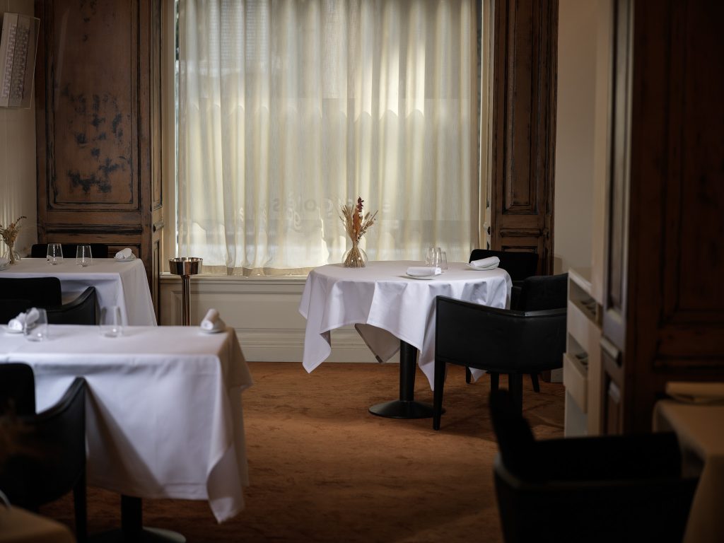 Salle de restaurant aux nappes blanches, lumière des grandes fenêtres