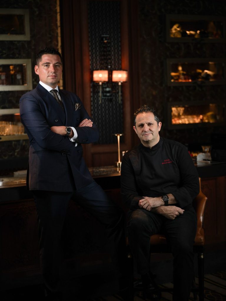Portrait de deux hommes en costume dans un bar à la lumière tamisée