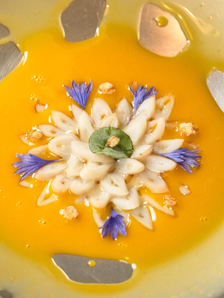 Assiette d’Alexandre Mazzia, pétales et bleuets sur un jus orangé