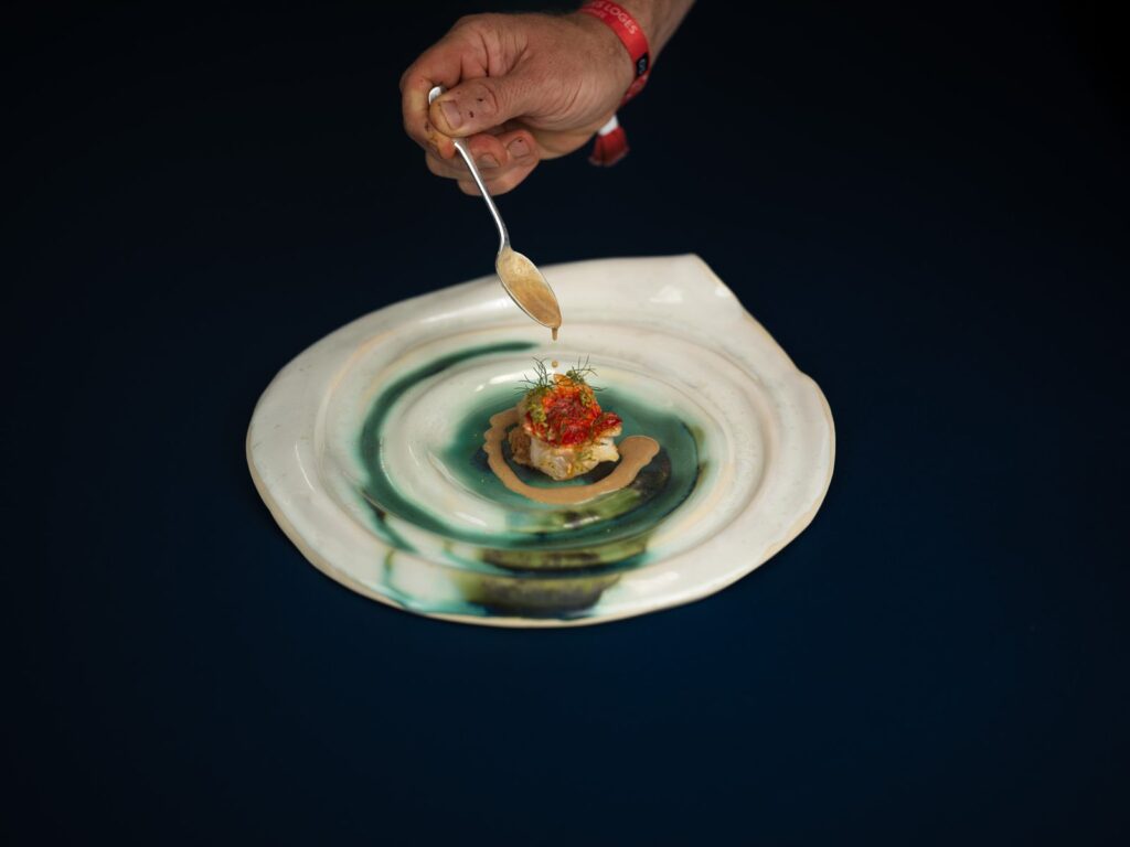 Sauce déposée à la cuillère sur une langoustine, assiette en céramique, Zostera